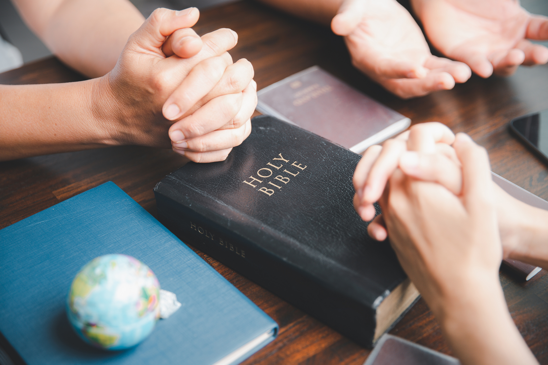 Concept of Christian ministry. Small groups pray together for Christian mission. Mission to spread the gospel and religion of Christianity around the world. hands praying with bible on wooden table.